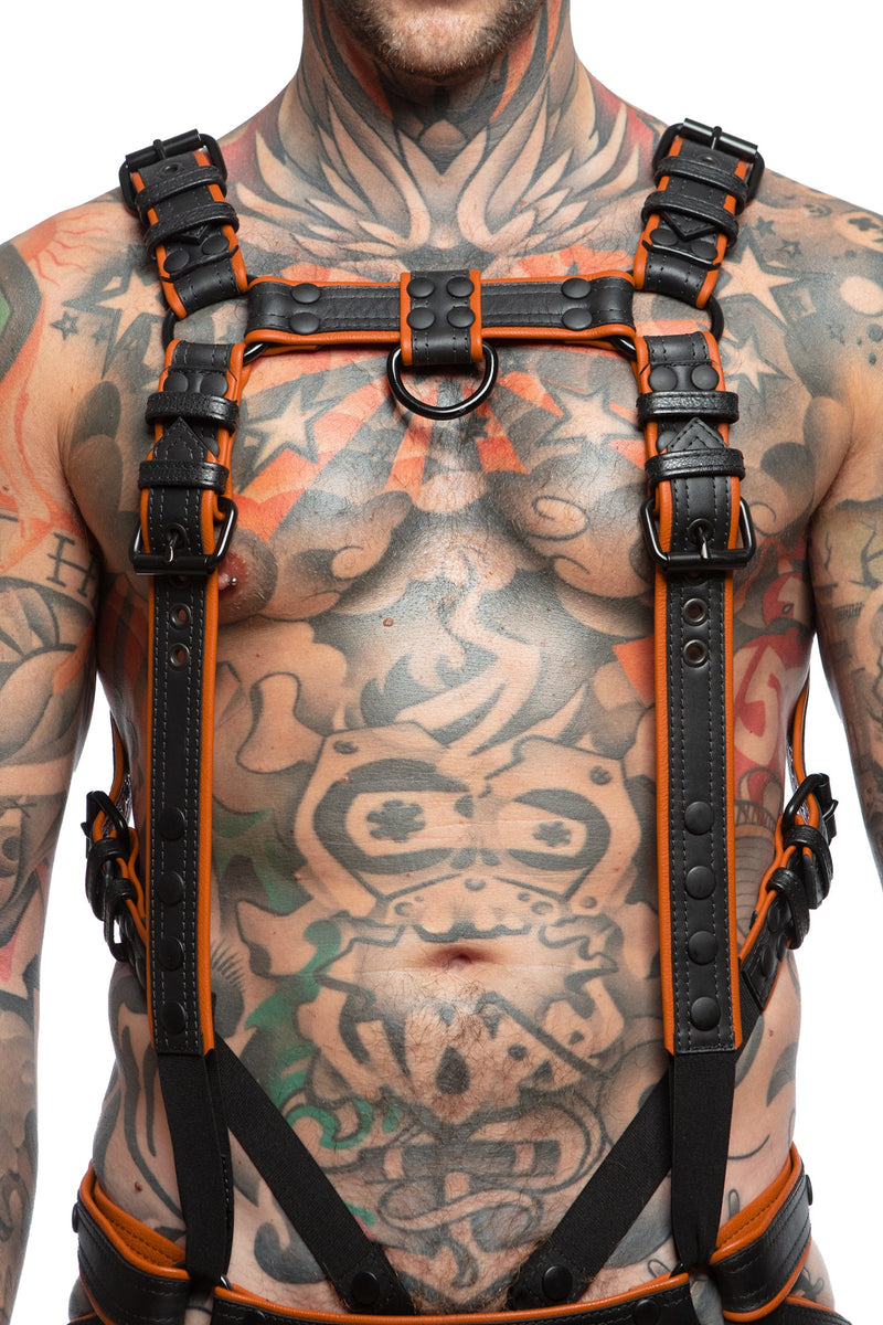 Model wearing a black and orange leather combat harness and connector with black metal hardware. Front view.