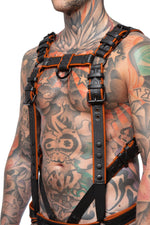 Model wearing a black and orange leather combat harness and connector with black metal hardware. Side view.