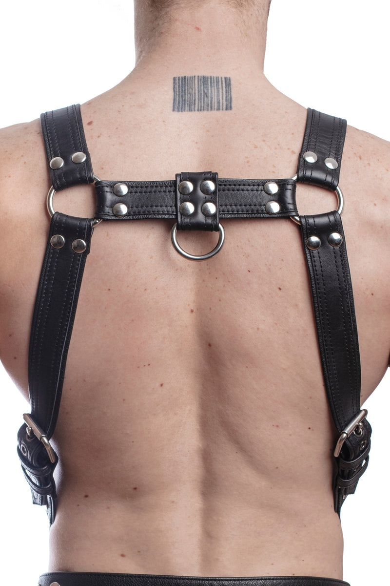 Model wearing a black leather combat harness and connector with stainless steel hardware. Back view.