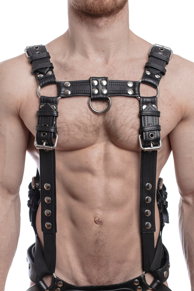 Model wearing a black leather combat harness and connector with stainless steel hardware, connected to a jock. Front view.