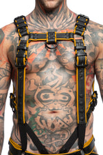 Model wearing a black and yellow leather combat harness and connector with black metal hardware. Front view.