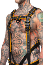 Model wearing a black and yellow leather combat harness and connector with black metal hardware. Side view.