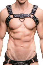 Model wearing a black leather combat harness with black metal hardware. Front view.