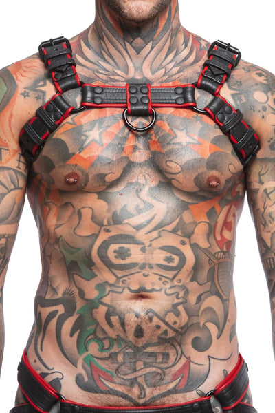 Model wearing black and red leather combat bulldog harness with matt black metal hardware. Front view.