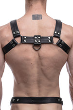 Model wearing a black leather combat harness with stainless steel hardware. Back view.