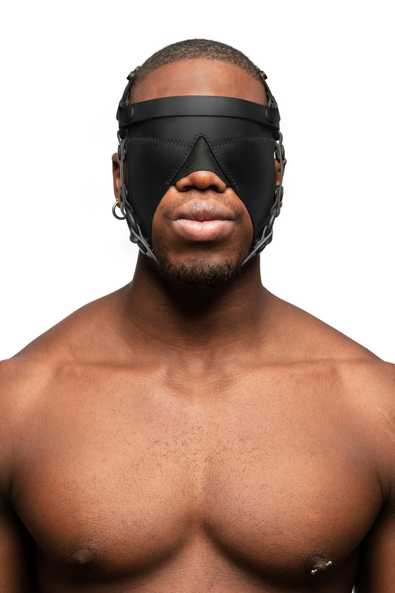 Model wearing black leather head harness and blinder with black metal hardware. Front view.
