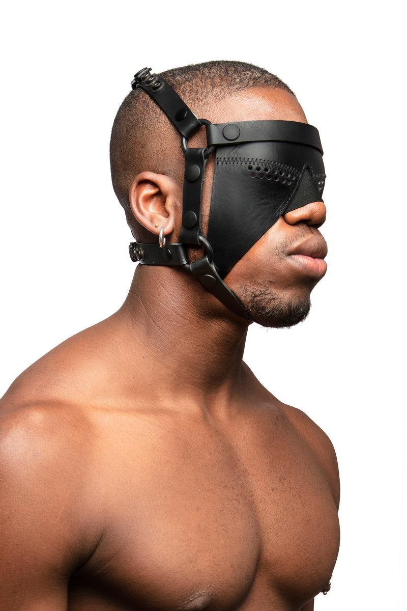 Model wearing black leather head harness and partial blinder with black metal hardware. Three quarter view.
