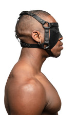 Model wearing black leather head harness and partial blinder with black metal hardware. Side view.