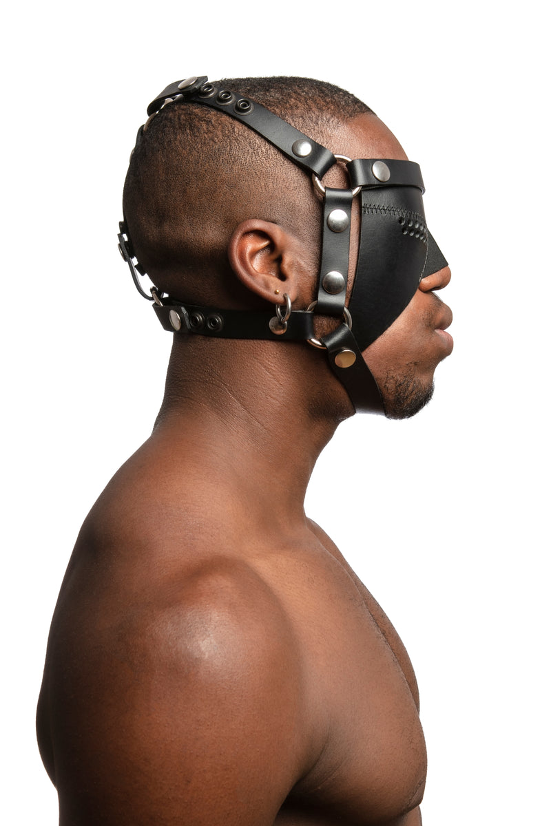Model wearing black leather head harness and partial blinder with stainless steel hardware. Side view.