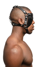 Model wearing black leather head harness and eye patch with stainless steel hardware. Side view.