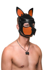 Model wearing a black and orange leather pup mask and head harness three quarter view