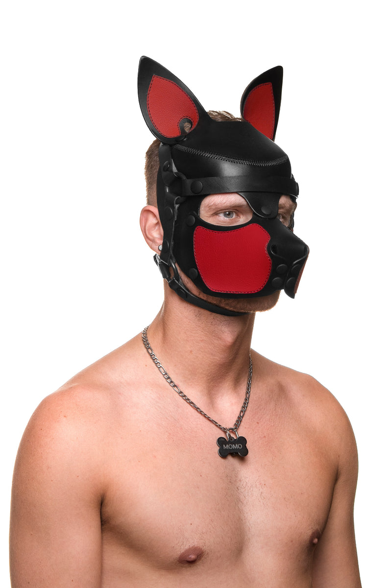 Model wearing a black and red leather pup mask and head harness three quarter view