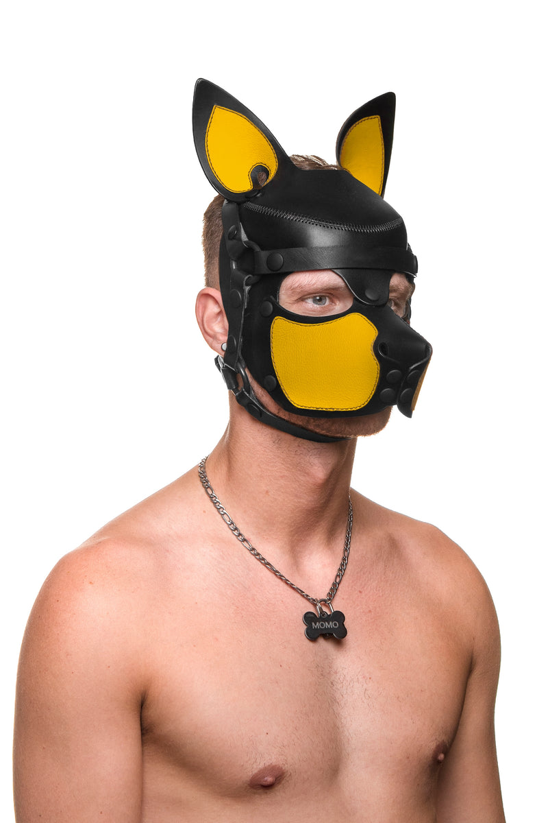 Model wearing a black and yellow leather pup mask and head harness three quarter view