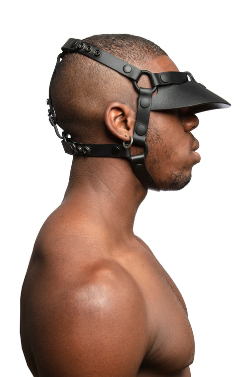 Model wearing black leather head harness and visor with black metal hardware.  Side view.