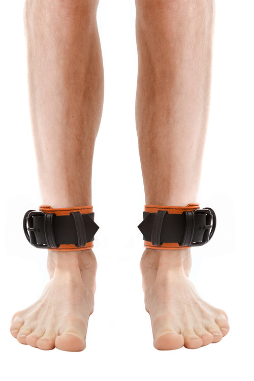 Model wearing orange and black leather ankle restraints
