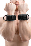 Model wearing grey and black leather wrist restraints
