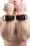 Model wearing orange and black leather wrist restraints