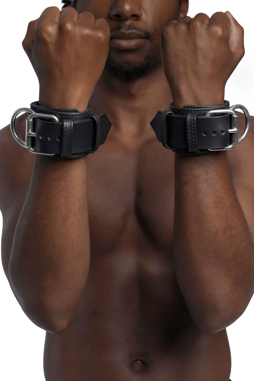 Model wearing black and stainless steel leather wrist restraints