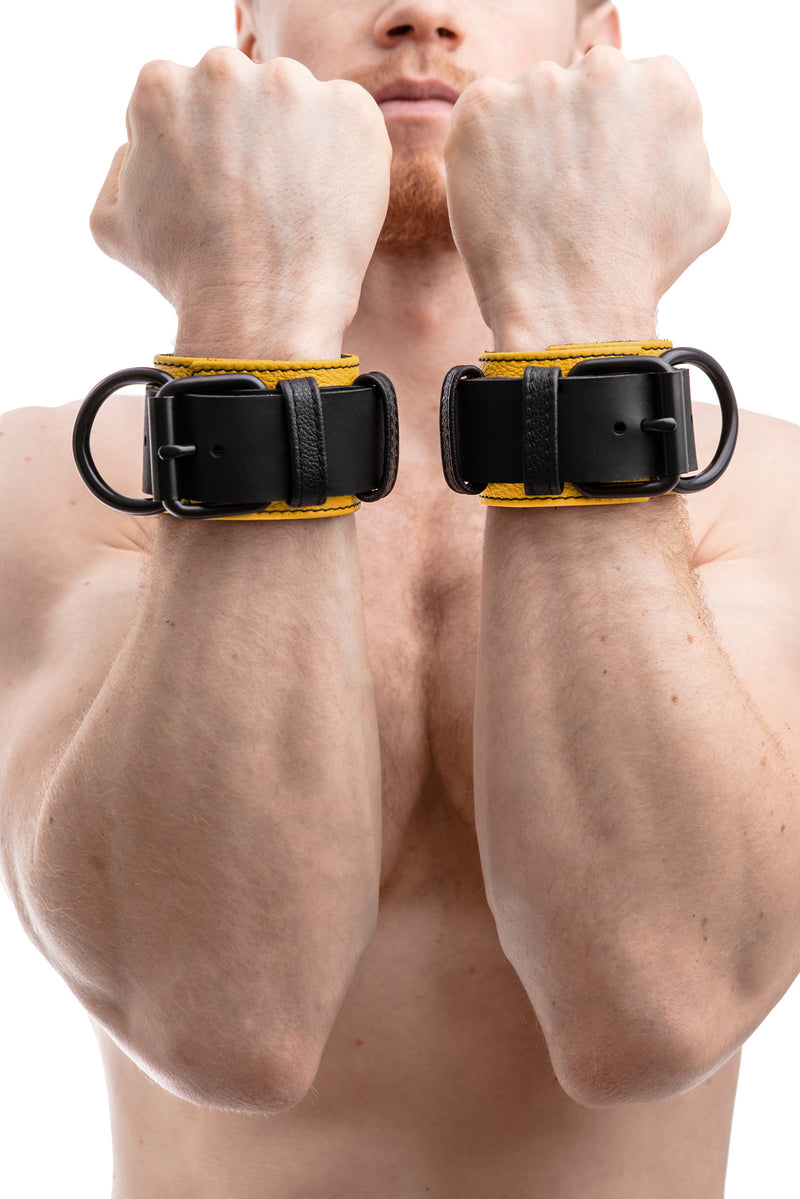 Model wearing yellow and black leather wrist restraints