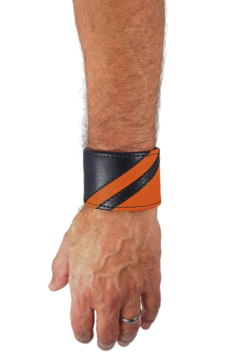 Model wearing a black leather wristband with orange leather chevron detailing. Left Wrist.