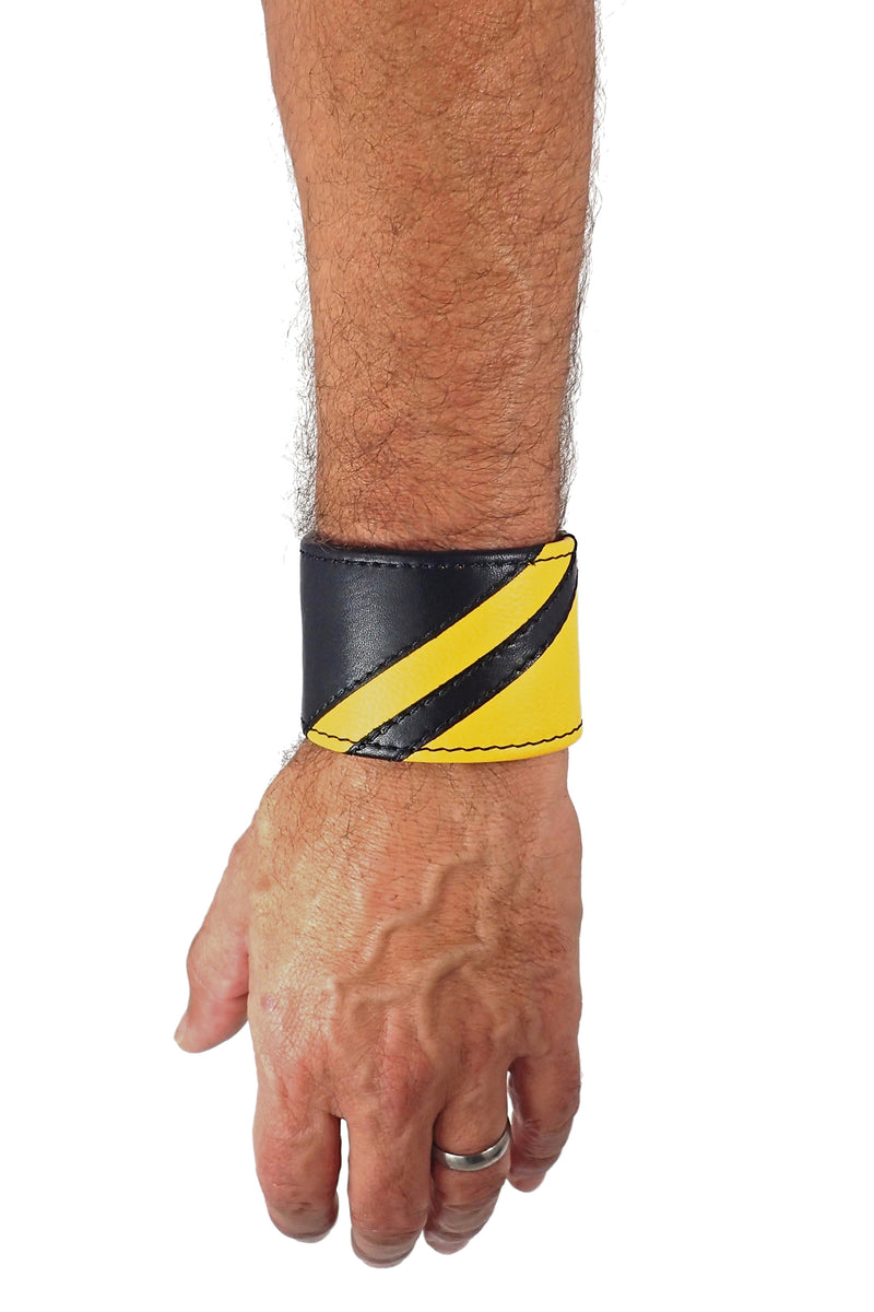 Model wearing a black leather wristband with yellow leather chevron detailing. Left Wrist.